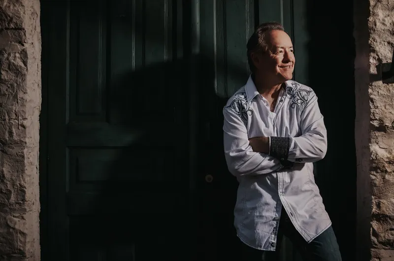 Bobby G. Rice, arms folded, in a white western shirt at a green door