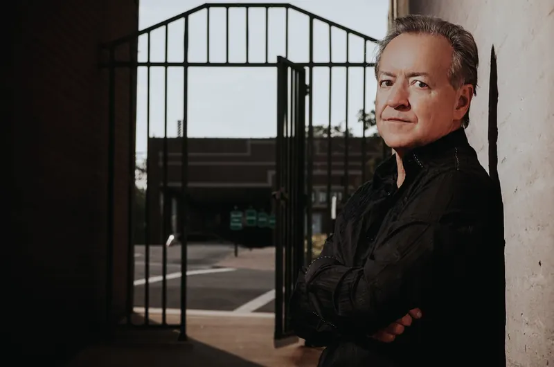 Bobby G. Rice, arms folded, beside an iron gate