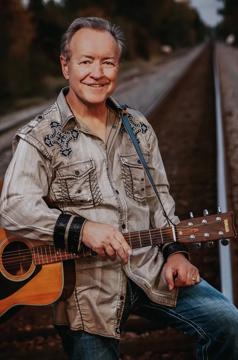 Bobby G. Rice with his acoustic guitar on the railroad tracks