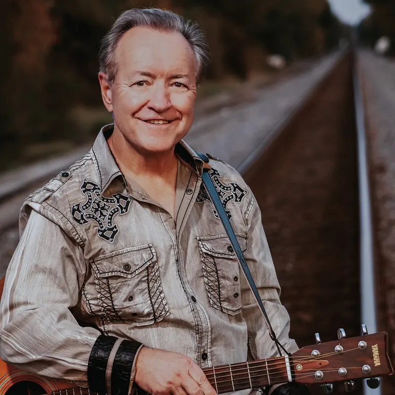 Bobby G. Rice up close, guitar in hand, beside the rails